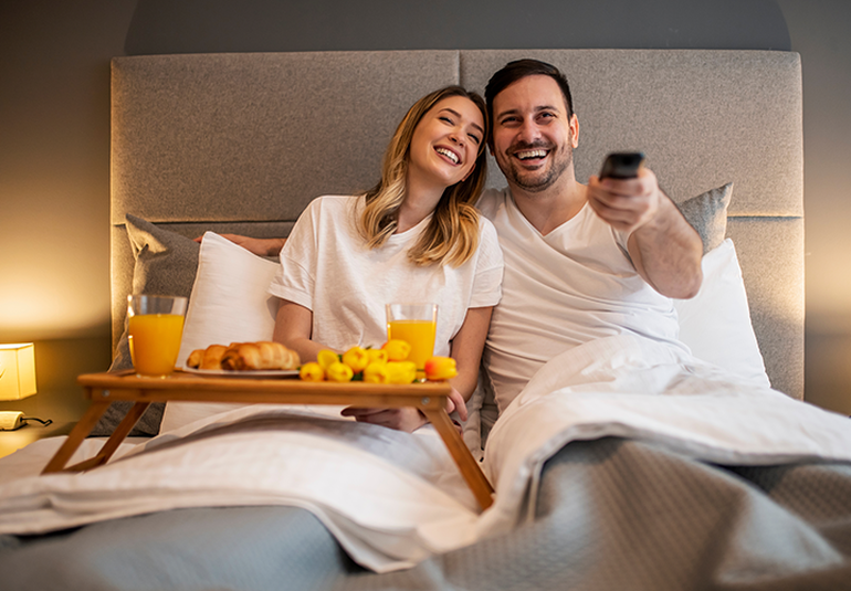 muž a žena v posteli s podnosom jedla