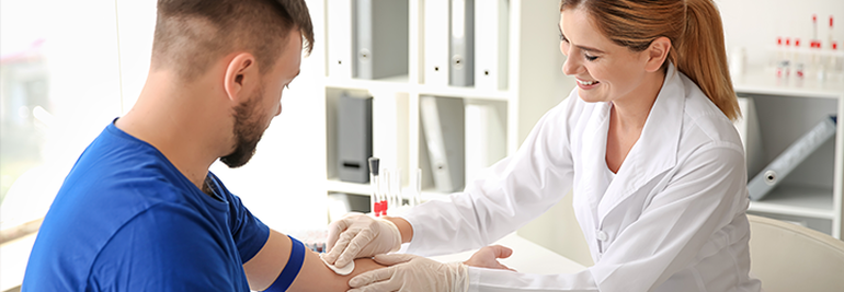 žena v bielom laboratórnom plášti dostáva vzorku krvi od muža