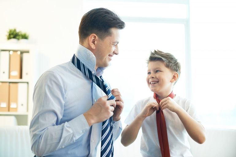 Otec a syn, ktorí si viažu kravatu.