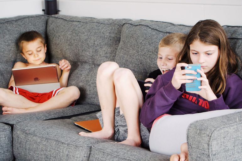 dve deti sedia na gauči a pozerajú sa na laptop 