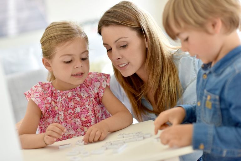 žena a dve deti sa pozerajú na kus papiera 