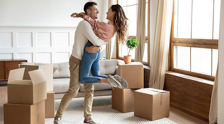 muž a žena stojaci v obývačke obklopení krabicami 