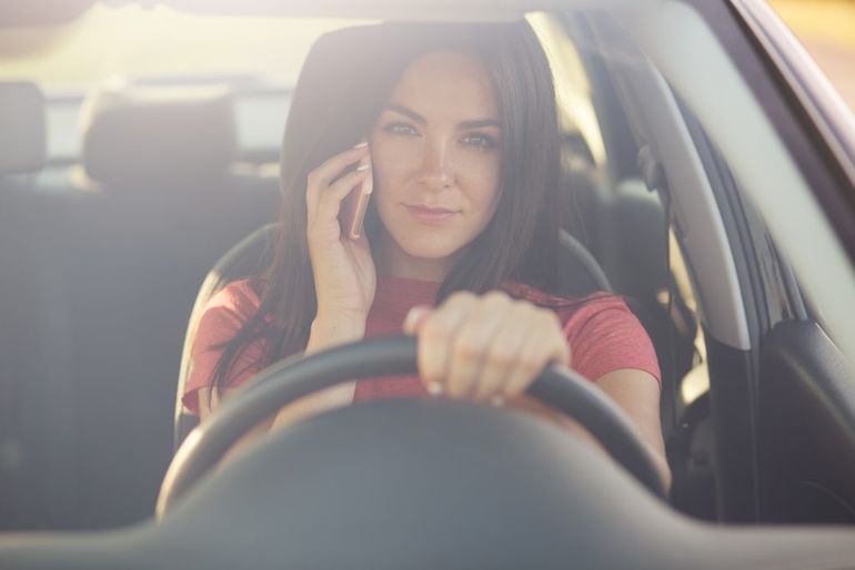 Žena telefonuje za volantom auta.