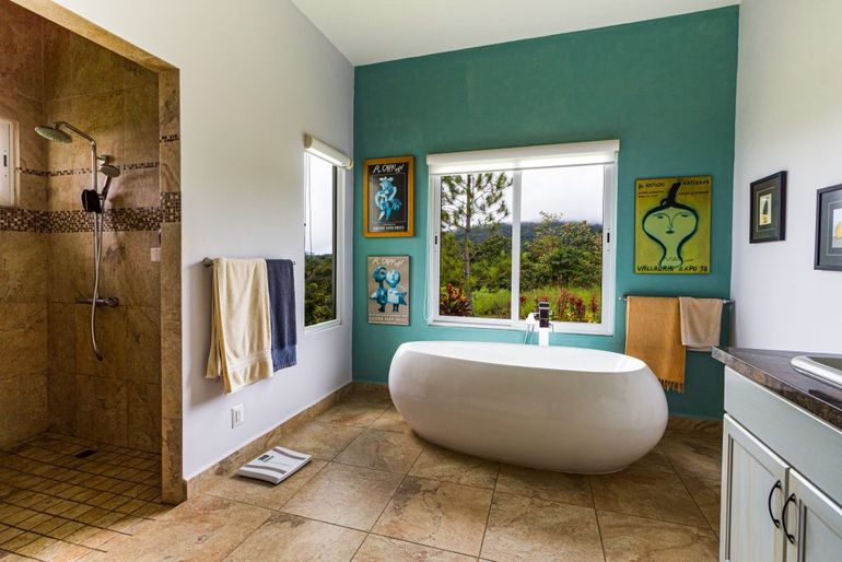 Veľká kúpeľňa s oknom a tyrkysovou stenou zdobenou zavesenými obrazmi.
